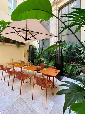 a group of tables with chairs and an umbrella at Maison Roma Piazza di Spagna UNA Esperienze in Rome