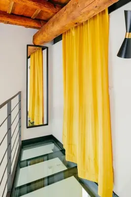 a staircase with a yellow curtain and a mirror at Charming restored loft in the heart of Trastevere in Rome
