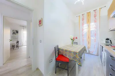 a white kitchen with a table with a vase of flowers on it at Amora Apartments in Rome