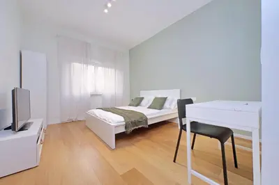 a white bedroom with a bed and a desk at Modern Family Apartment in Rome