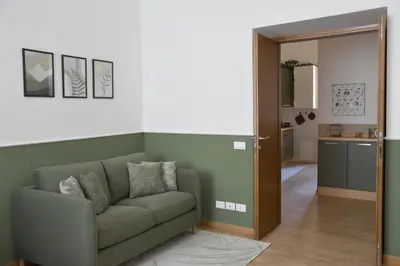 a living room with a green couch and a kitchen at RoMa Apt In Vatican in Rome