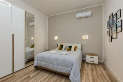 a white bedroom with a bed and a large mirror at Casa di Azzurra in Rome