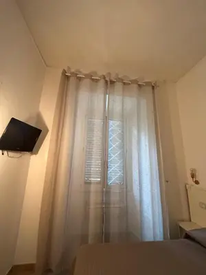 a bedroom with a white curtain and a window at Don sweet home-Hedi in Rome