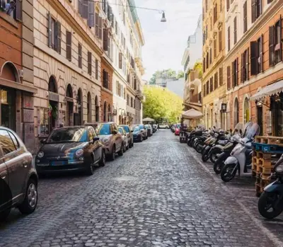 a cobblestone street with parked cars and buildings at Charme Holidays Trastevere in Rome
