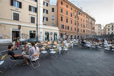 a group of people sitting at tables on a city street at Urban Oasis near Termini with Patio, int1b in Rome