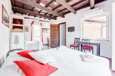 a bedroom with a large white bed with red pillows at Romantic house with terrace in Rome