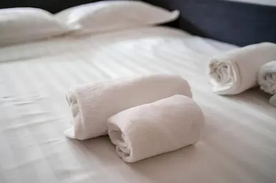 two rolls of white towels on a bed at 5 Min From Trastevere Rome Chic Apartment in Rome