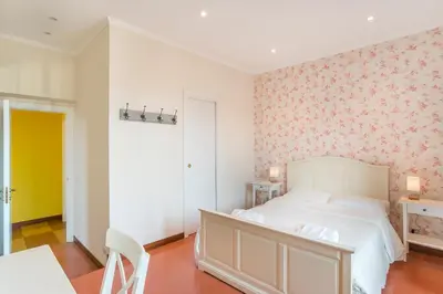 a bedroom with a white bed with a floral wallpaper at Casa di Alice in Rome