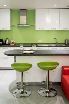 a kitchen with a counter with two green bar stools at NEW Mini Loft per 5 a Roma centro in Rome