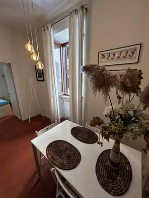 a white table with a vase of flowers on it at Colosseum Apartment - Your Cozy Roman Escape in Rome