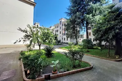 a courtyard with trees and plants in front of a building at Typical roman home in Testaccio in Rome