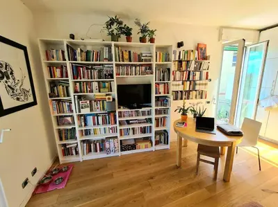 a living room with a table and book shelves filled with books at Incantevole bilocale a Città Giardino in Rome