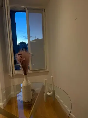 a glass table with a vase and a window at Forte's Apartment in Rome