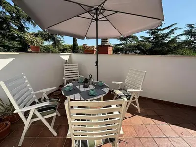 a table and chairs with an umbrella on a patio at Vatican Green Penthouse in Rome