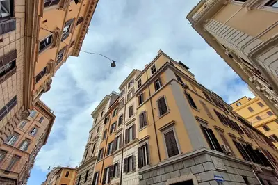 a tall building in the middle of some buildings at Caprareccia In Monti by Halldis in Rome