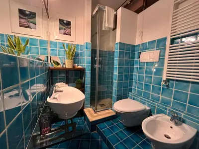 a blue tiled bathroom with a toilet and a sink at A Terrace With a View in Rome