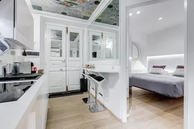 a kitchen with white cabinets and a bed in a room at Colosseum Charming Suite monti district with jacuzzi in Rome