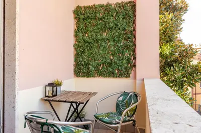 a table and chairs on a balcony with a green wall at Casa Cornelia 10 MIN to metro, near Vatican in Rome