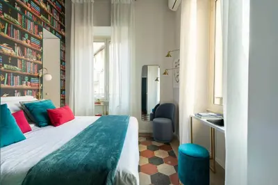 a hotel room with a bed with red and blue pillows at YCH-Colosseo book house in Rome