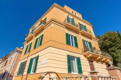 a tall yellow building with green shuttered windows at Elegantis Des Artistes Apartment in Rome