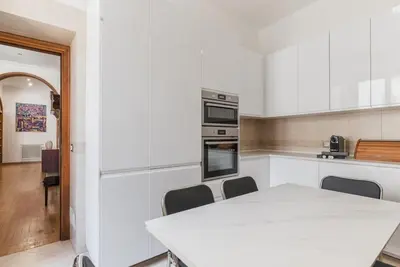 a white kitchen with a table and chairs at Charme e Lusso a San Pietro in Rome