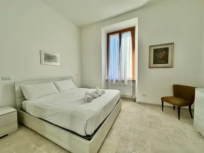 a white bedroom with a bed and a chair at Giuli-Etta a Testaccio in Rome