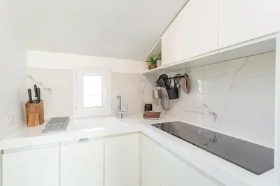 a white kitchen with white cabinets and a sink at Radice Home in Rome