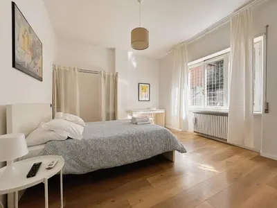 a white bedroom with a bed and a table at Vatican House big in Rome