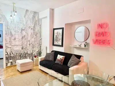 a living room with a black couch and a no bad vibes mural at Exclusive Apartment in the Heart of Rome in Rome
