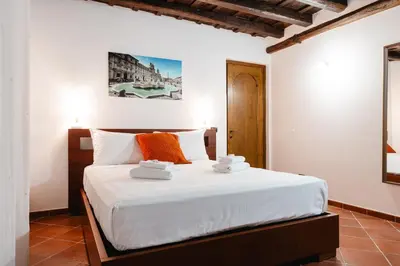 a bedroom with a bed with white sheets and orange pillows at Domus LXVII Monti in Rome