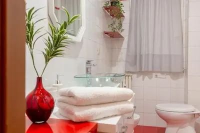 a bathroom with a red vase on a counter with towels at Stanza Comoda e Silenziosa con Bagno Privato e Area Lavoro e Relax in Rome