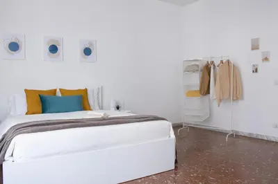 a white bedroom with a large white bed with orange and blue pillows at Tommys flat by DomusDimore in Rome