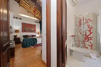 a bathroom with a toilet and a bed in a room at Piazza Venezia Apartment in Rome