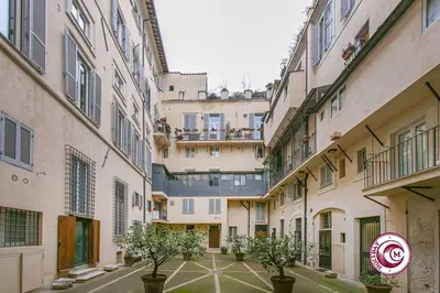 an alley between two buildings with trees in pots at Palazzo Scapucci Apartment a Navona in Rome