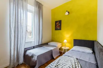 two beds in a room with a yellow wall at Santonofrio Apartments in Rome