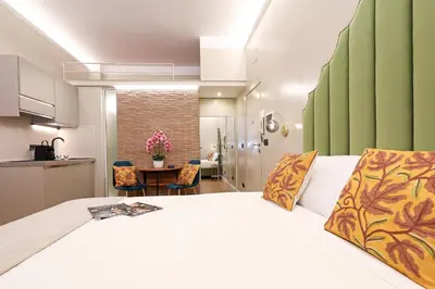 a bedroom with a white bed and a kitchen at Vatican Loft - Liberty Collection in Rome