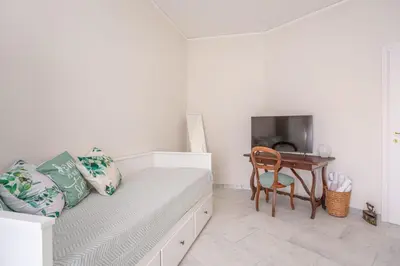 a white bedroom with a bed and a table at Roma is amoR in Rome