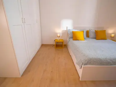 a white bedroom with a bed with yellow pillows at 2BDR Testaccio Sweet Home in Rome