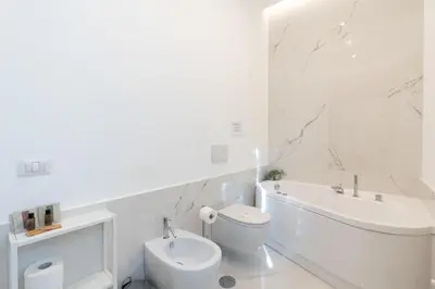 a white bathroom with a toilet and a tub and a sink at Elegante Appartamento presso Vaticano in Rome