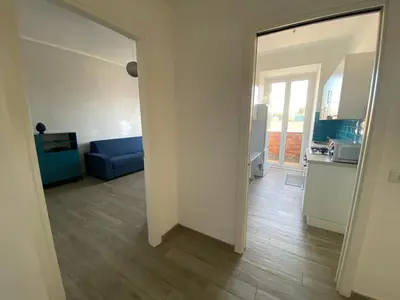 a living room with a blue couch and a kitchen at Lola's house in Rome
