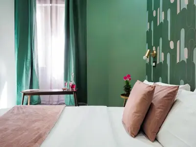 a bedroom with a white bed with a green wall at C'est La Vie Suites in Rome
