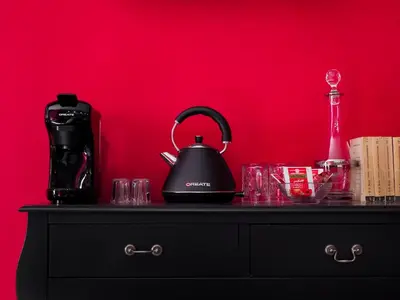 a black tea kettle and glasses on a dresser against a red wall at C'est La Vie Suites in Rome