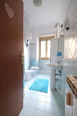 a bathroom with two toilets and a blue rug at Guest House Piazza Tarquinia in Rome