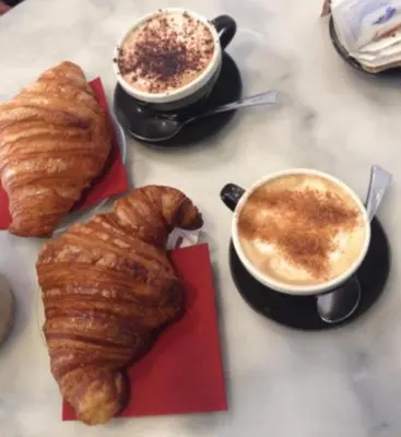 a table with two cups of coffee and two croissants at Guest House Piazza Tarquinia in Rome