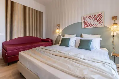 a bedroom with a large bed and a red couch at Dafne Rooms un soggiorno energico e pieno di vita in Rome