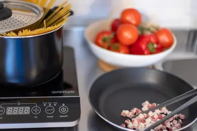 a pan with meat on a stove with a bowl of tomatoes at Dafne Rooms un soggiorno energico e pieno di vita in Rome