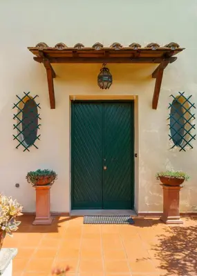 a green door on a house with two potted plants at Villa Mara Appia antica in Rome