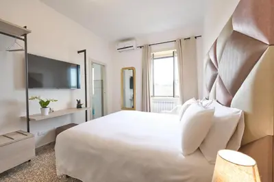 a hotel room with a white bed and a television at B&B ErinaHouse in Rome