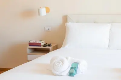 a white bed with a pile of towels on it at Porta Pia apartment ZENO 53 in Rome