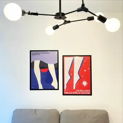 two framed posters on a white wall with a couch at Simposio - Luxury Apartment Rome in Rome